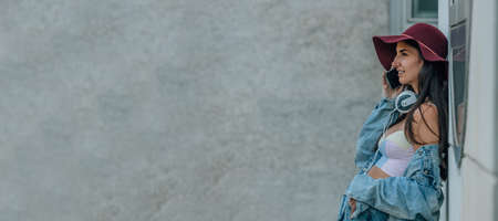 girl with hat talking on mobile phone on the wall in the streetの写真素材