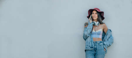 girl with hat talking on mobile phone on the wall in the street
