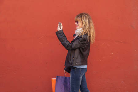 woman with shopping bags isolated on the wall in the street outdoors