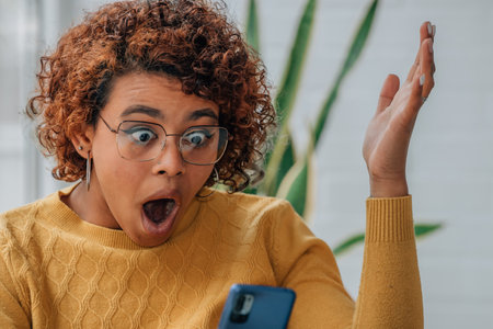 girl at home looking at mobile phone surprisedの写真素材