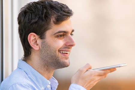 young man with mobile phone sending voice message