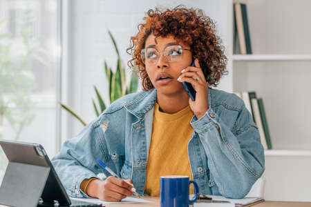 girl with mobile phone and laptop at home or in the officeの写真素材