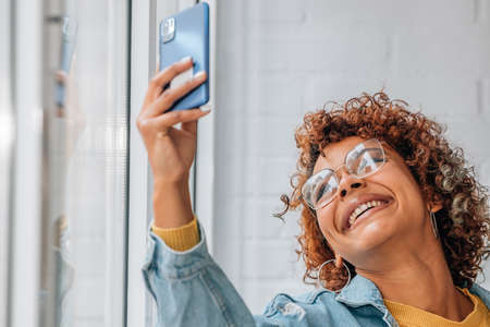 smiling girl taking photo or recording with mobile phone