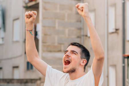 happy young man celebrating with joy outdoorsの写真素材