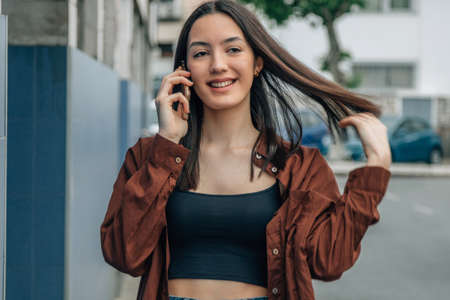 smiling young girl talking on mobile phone in the streetの写真素材