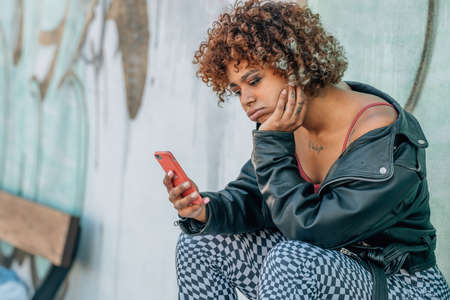 girl on the street bored looking at the mobile phoneの写真素材
