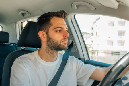 young man behind the wheel of the car drivingの写真素材