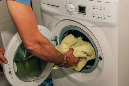 hand putting clothes to wash in the washing machineの写真素材