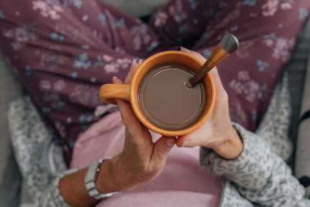 top view of hands with cup of coffee of relaxed woman at homeの写真素材