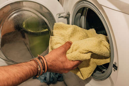 hand putting clothes to wash in the washing machineの写真素材