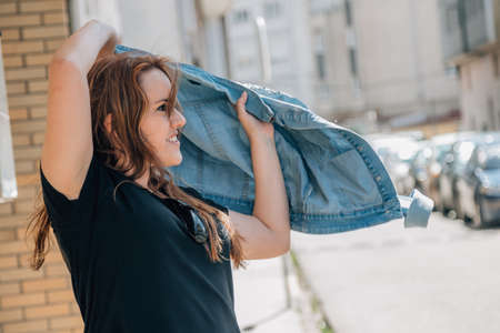 girl in the street putting on her jacketの写真素材