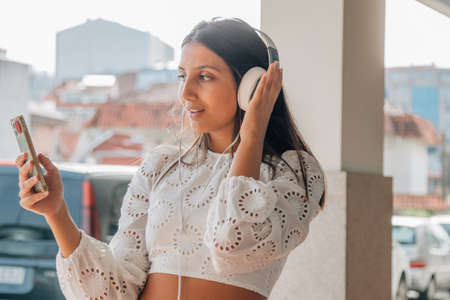 latin girl with headphones and mobile phone or smartphone listening to musicの写真素材