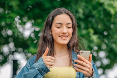 girl with okay signal looking at the mobile phone
