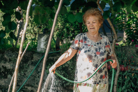 senior woman in summer watering the vegetable garden