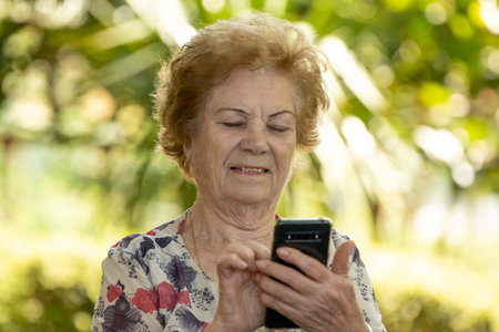 senior woman with mobile phone or cell phone outdoorsの写真素材