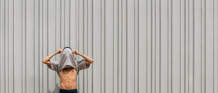 young man celebrating in the street with t-shirt on his head