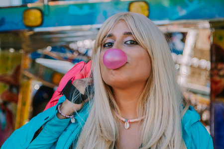 girl with gum making a balloon in the amusement parkの写真素材
