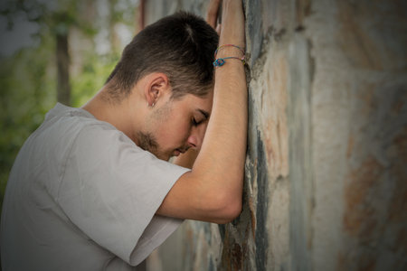depressed young man leaning on the wallの写真素材