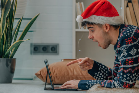 young man at christmas at home with computer and expression of surpriseの写真素材