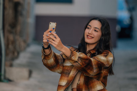 girl on the street in autumn style with mobile phoneの写真素材