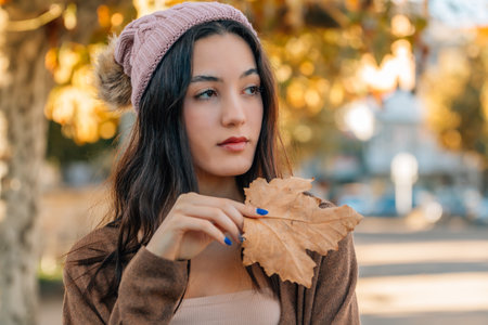 portrait of young millennial girl on the street outdoors with autumn leavesの写真素材