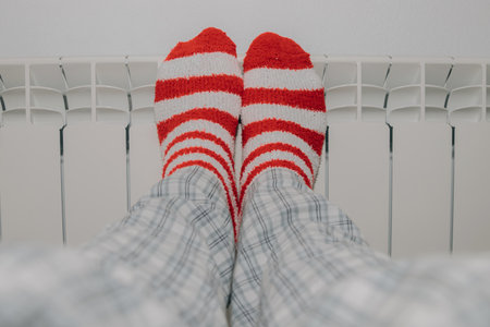 feet in striped socks on the heating radiator at homeの写真素材
