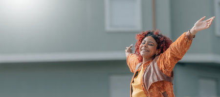 latin black woman smiling with happiness with arms raised in the street outdoorsの写真素材