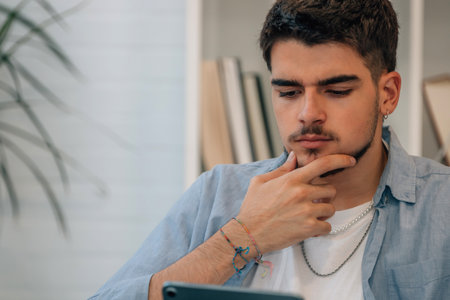 young man at home with tablet pensive, doubt or decision