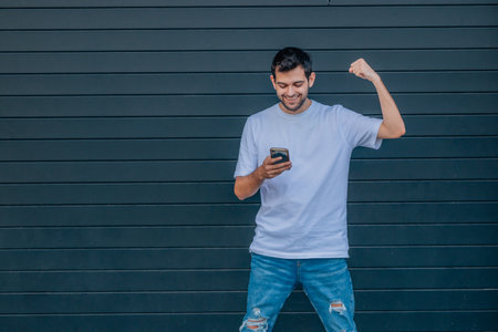 young man with mobile phone in the street with successful expression
