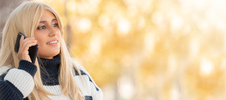 portrait of woman talking on the phone outdoors in autumnの写真素材