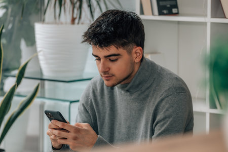 young man at home with mobile phone or smartphone