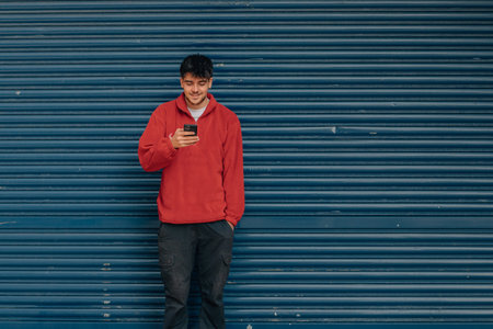 young man with mobile phone in the street with blue background
