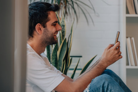 young man at home with mobile phone or deviceの写真素材
