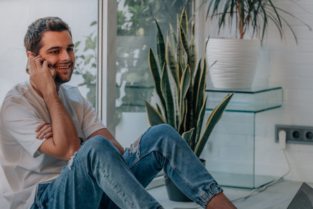 young man at home talking on mobile phoneの写真素材