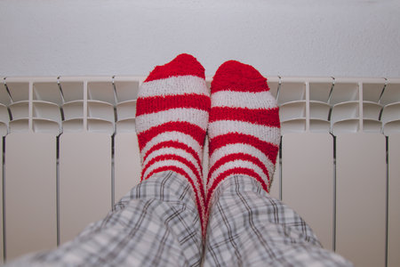 feet in striped socks on the heating radiator at homeの写真素材