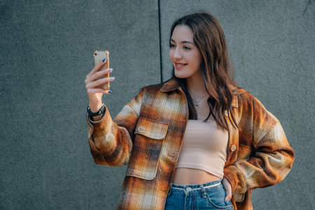 urban young woman in the street with mobile phone and autumn outfitの写真素材