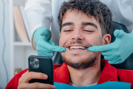 patient at the dentist looking with mobile phoneの写真素材