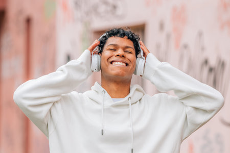 happy young man enjoying listening to music with headphones in the streetの写真素材
