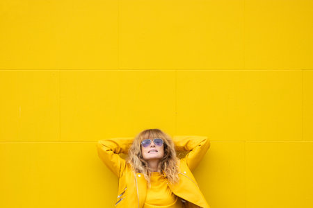 happy relaxed middle age woman on yellow wall in the street