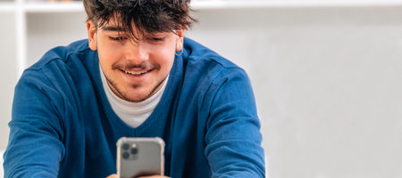young male student looking at mobile phone smiling