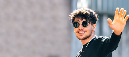 young man on the street waving
