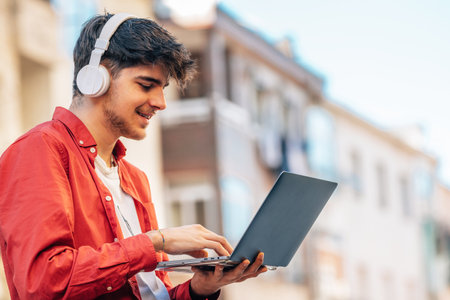 young man with laptop and headphones outdoors in the cityの写真素材
