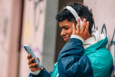 young urban latino man with mobile phone and headphones in the streetの写真素材