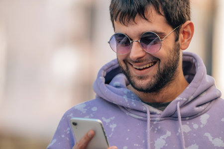 young man in sunglasses on the street with mobile phone