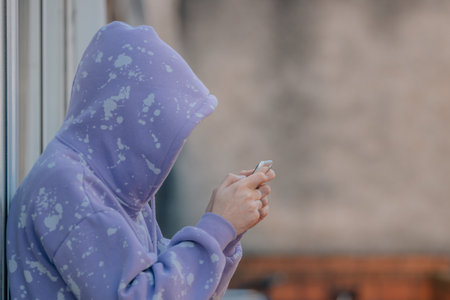 young man covered or hidden in the street with mobile phone