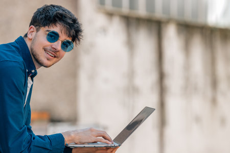 boy with sunglasses and laptop on the street