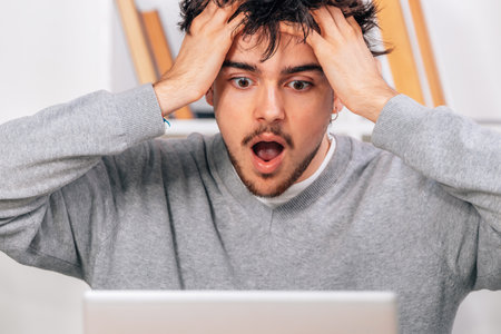 young man with laptop and surprised expression