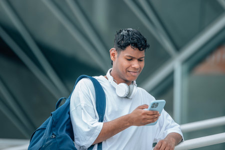 young latino male in the street looking at the mobile phone