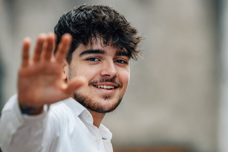 portrait of young male in the street saying goodbye or greetingの写真素材