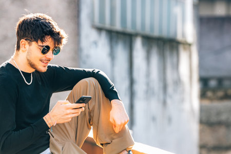 portrait young urban man with sunglasses and mobile phone in the streetの写真素材